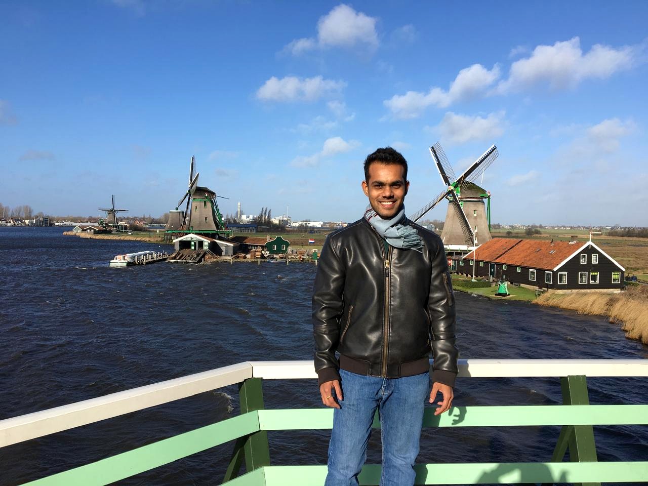 Bhavesh Jain standing on a bridge in front of Dutch windmills